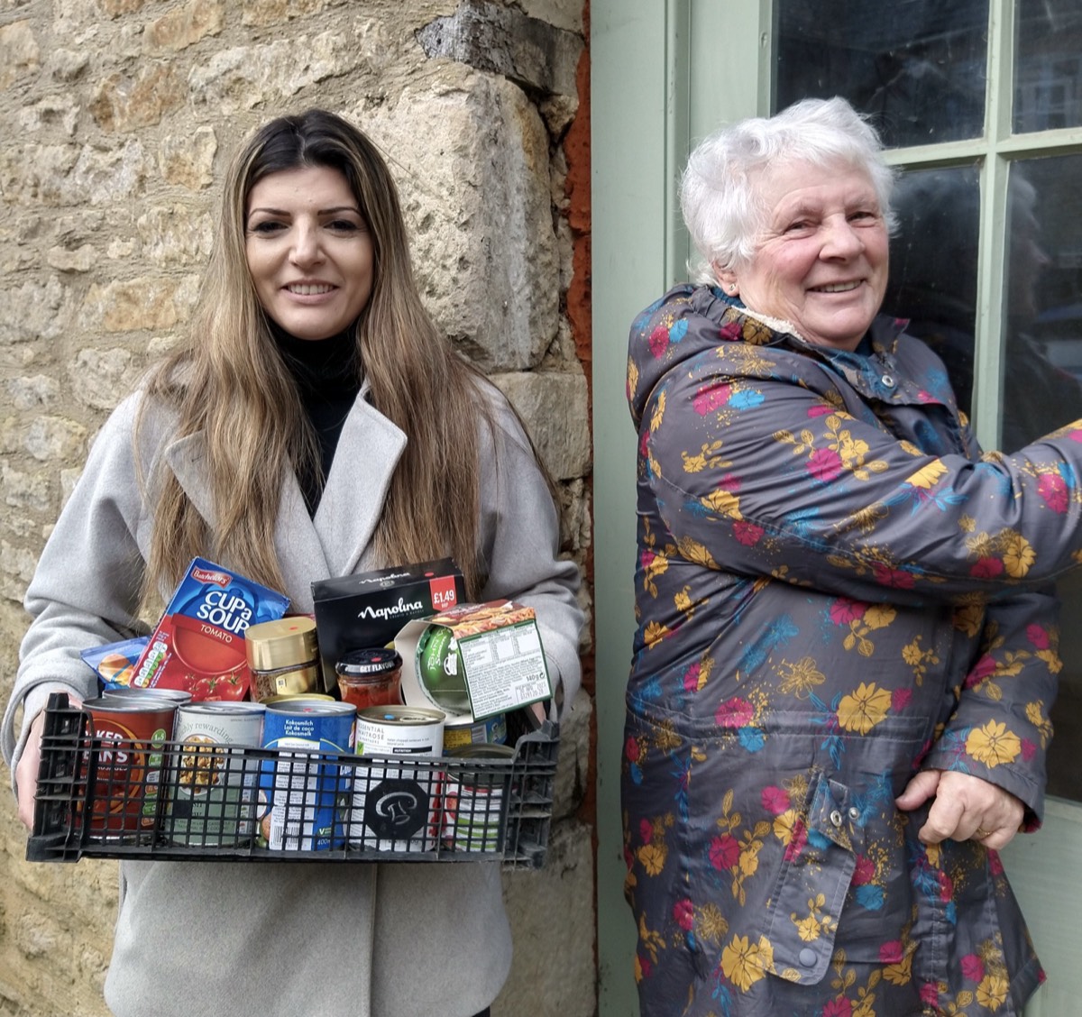 Two Besom volunteers, one holding a crate of donated food
