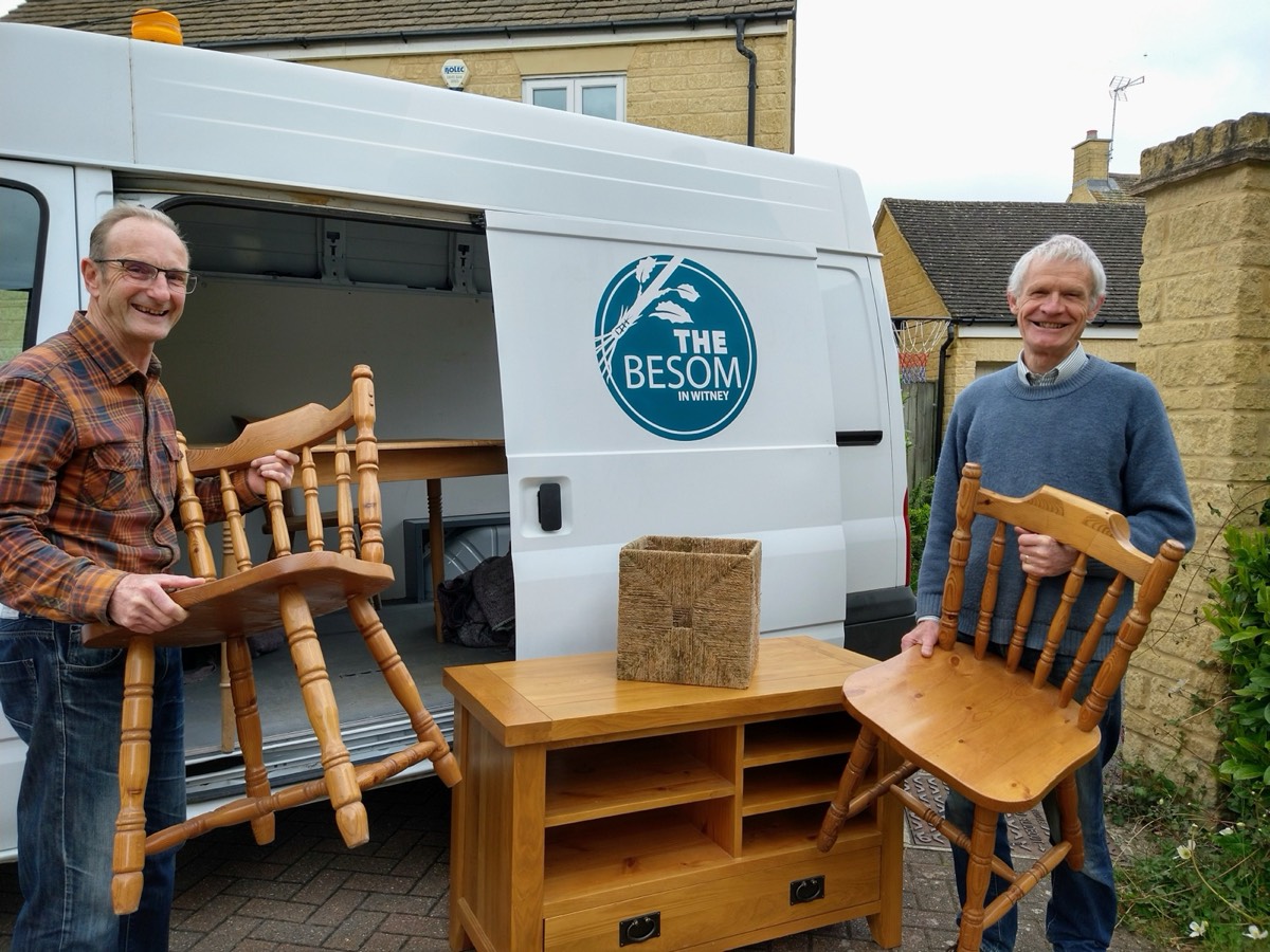 Two volunteers unloading donated chairs and a cabinet from the Besom van