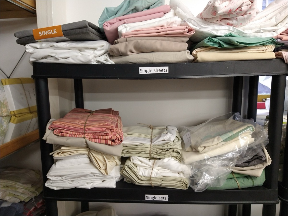 Shelves of folded, donated sheets and bedding sets