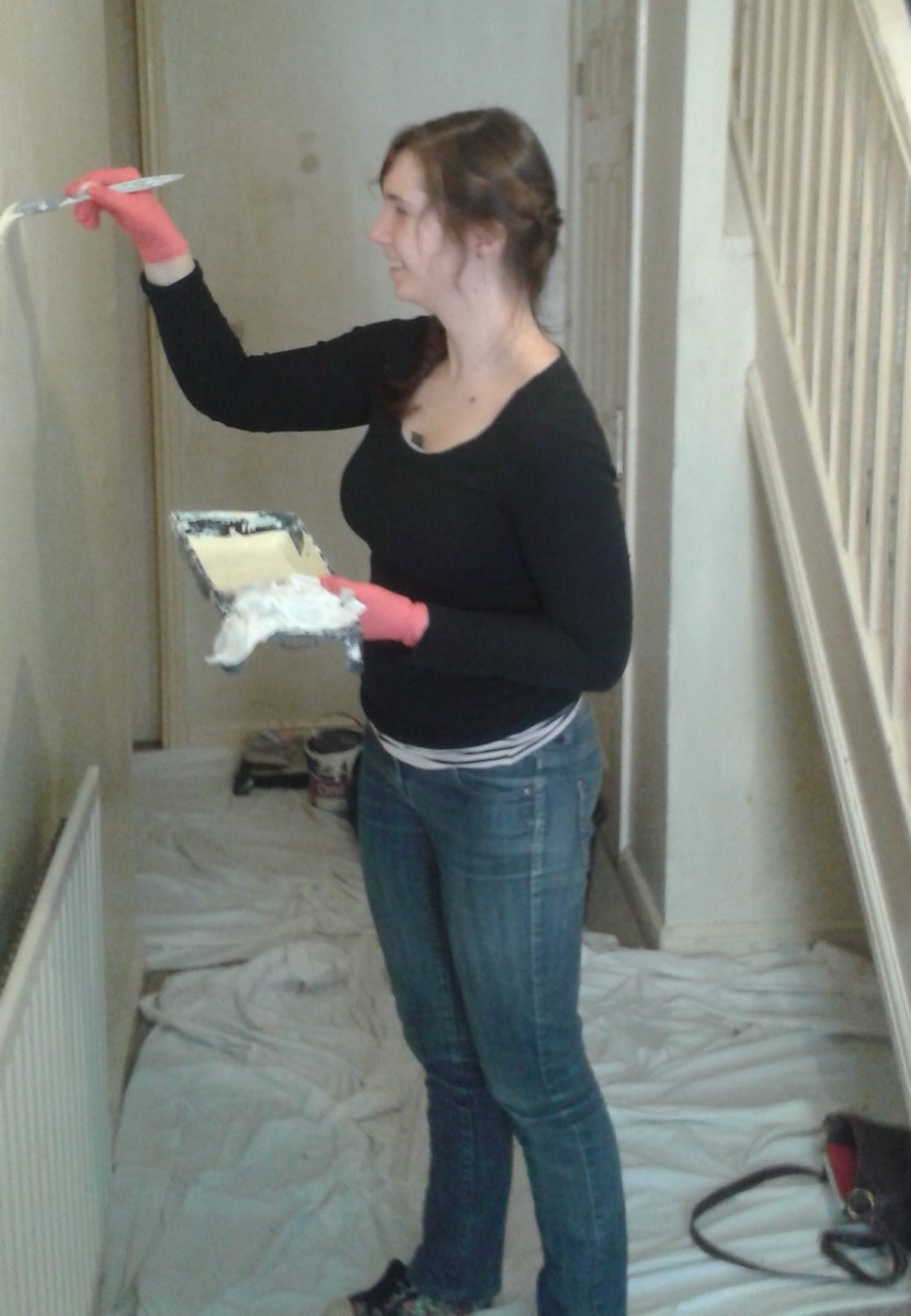 A volunteer painting a hallway wall
